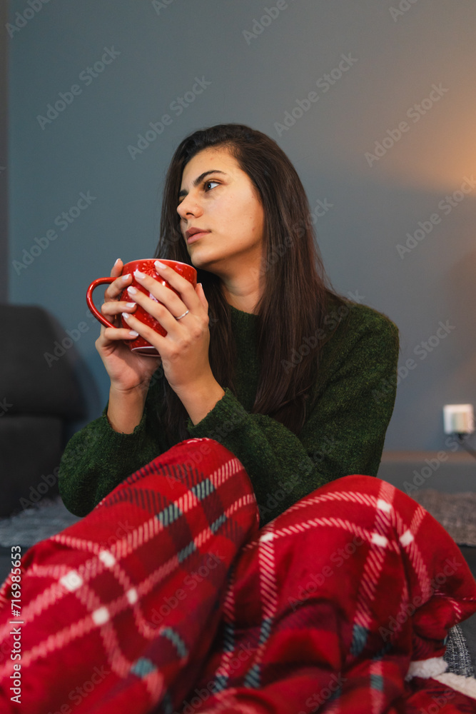 A young girl or woman getting up from bed drinking coffee or tea in blanket cozy room A young girl or woman getting up from bed drinking coffee or tea in blanket cozy room