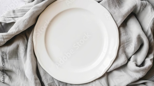 Empty white ceramic plate on a gray linen cloth.