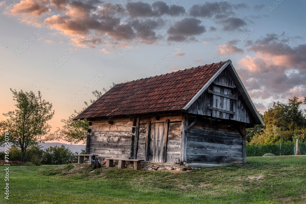 Beautiful sunset in the vineyard of the village with a wooden house