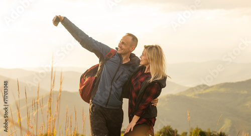 Stampa su tela A man and a woman in tourist equipment are standing on a rock and admiring the panoramic view