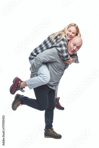 Laughing dad and adult daughter are fooling around. A young pretty blonde on the back of a bald man. Love and tenderness. Isolated on a white background. Vertical. Full height.