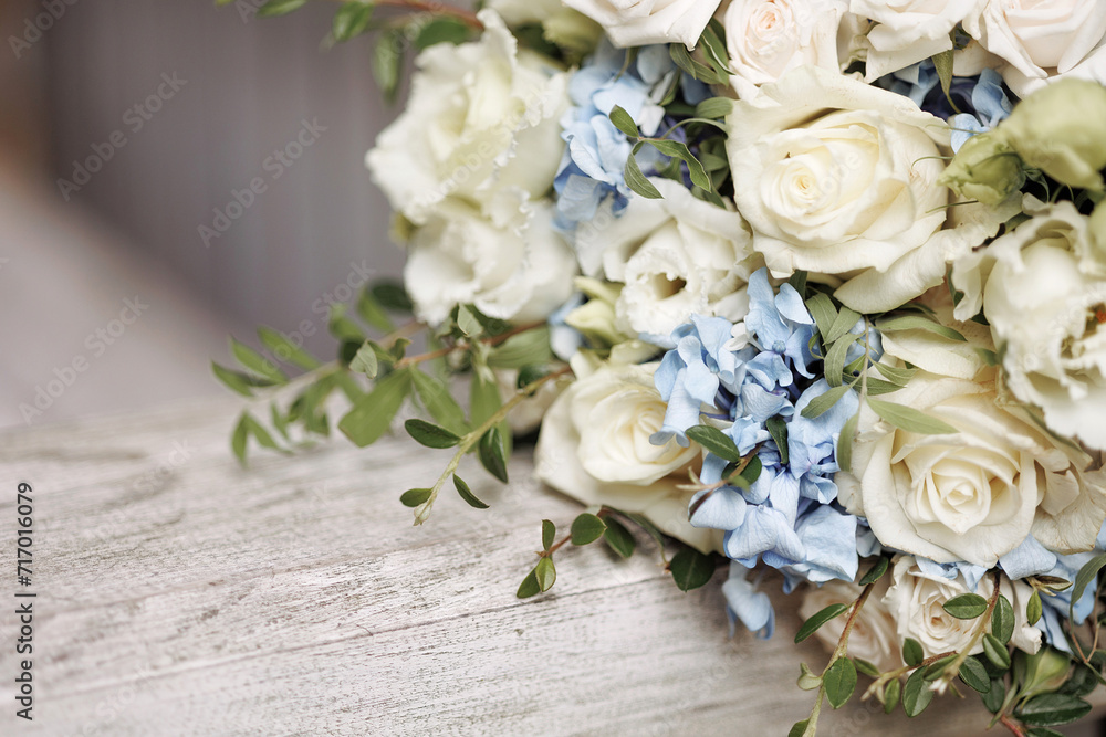 An elegant bouquet with blooming white roses and delicate blue flowers rests on a wooden railing. Concept for wedding arrangements, floral designs, or romantic events. An elegant bouquet with blooming white roses and delicate blue flowers rests on a wooden railing. Concept for wedding arrangements, floral designs, or romantic events.