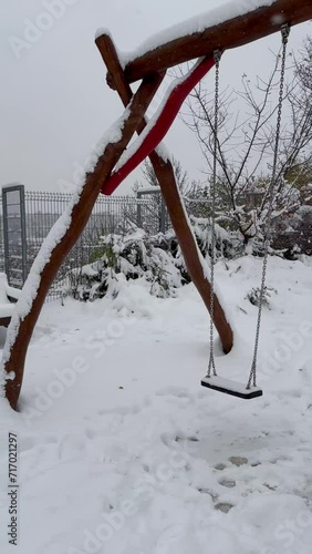 Lonely swings at empty children's playground covered with snow. Winter solitude. Prague. photo