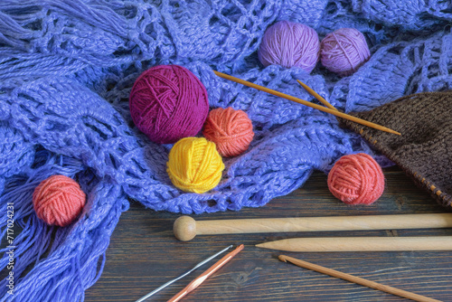 Knitting and hobby concept. Colorful balls of wools, knitting needles and сrochet hooks on rustic table