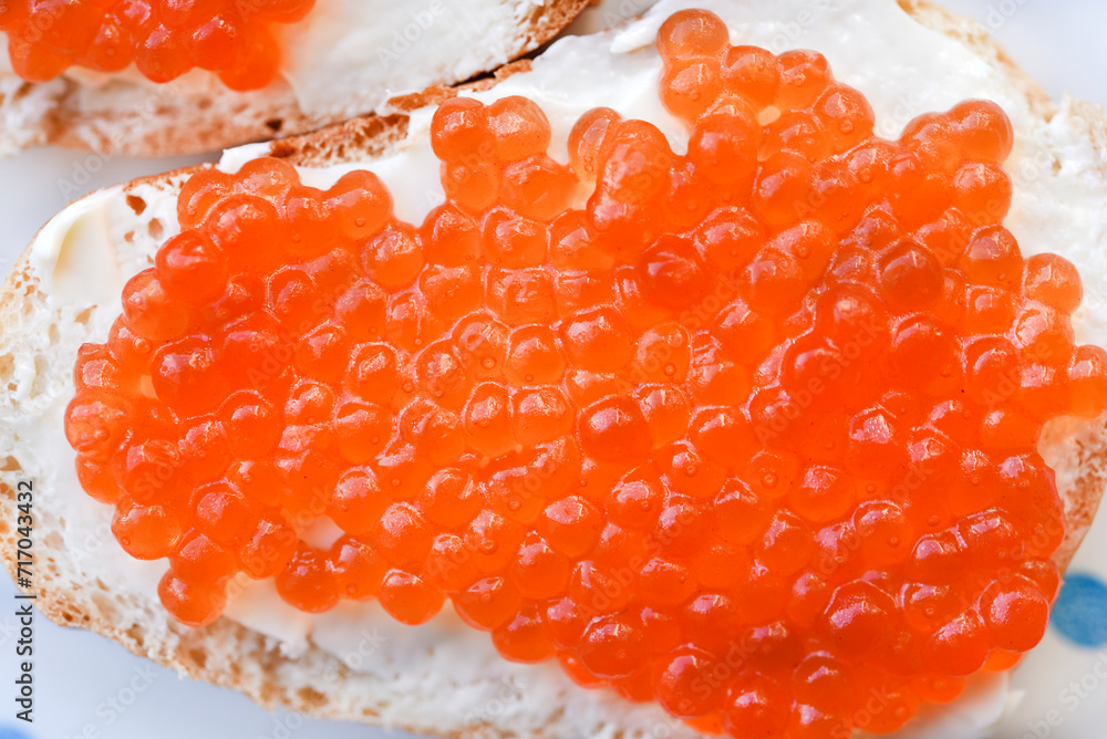 Red salmon caviar on bread and butter. A sandwich with caviar and butter on a plate. Red salmon caviar on bread and butter. A sandwich with caviar and butter on a plate.