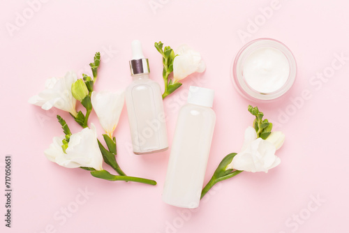Facial cosmetic products with freesia flowers on color background  top view