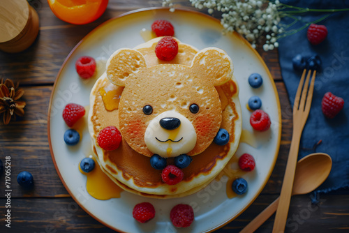 Funny food for kids. Bear shaped pancakes with berries on blue wooden table, top view