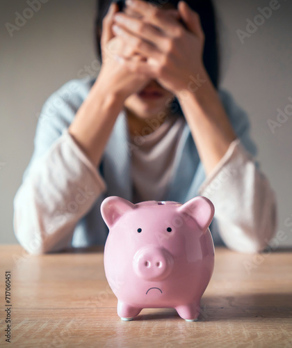 Sad girl with a piggy bank at home.