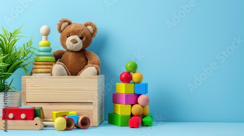 Container with teddy bear, wooden rattles, stacking pyramid and wood blocks on light blue background © Chingiz