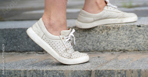 A girl walks up the stairs in the city outdoors  legs in the sneakers closeup.
