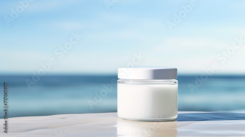 White cream jar sitting on a flat surface with copy space and ocean behind photo