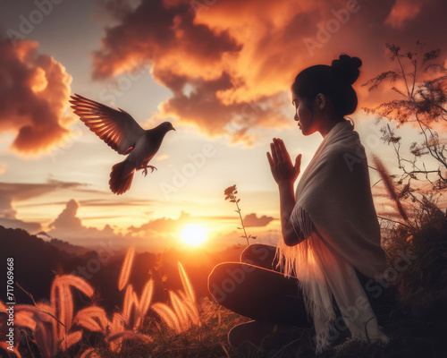 Woman pray to God near bird at sunset