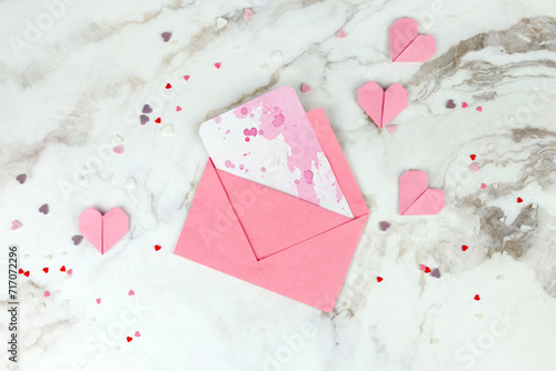 paper envelope and paper pink hearts on a marble background. Valentine's Day concept