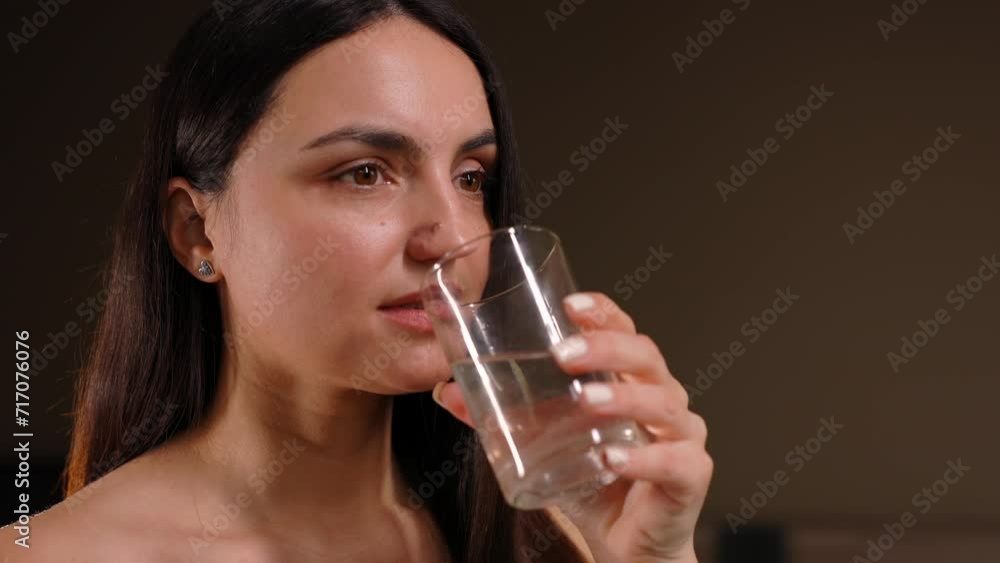 Pretty brunette drinking water standing near bed at home in the bedroom. Pretty brunette drinking water standing near bed at home in the bedroom.