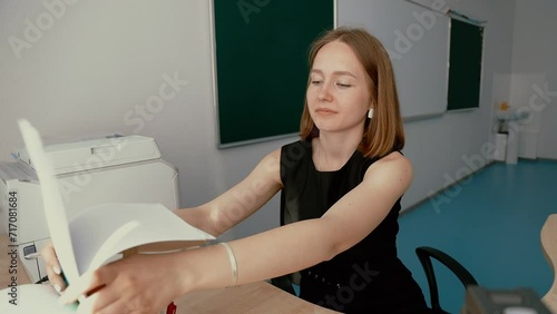 Young woman teacher inserting paper into printer