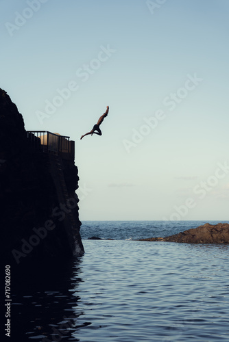 Persona saltando hacia una piscina natural (ID: 717082690)