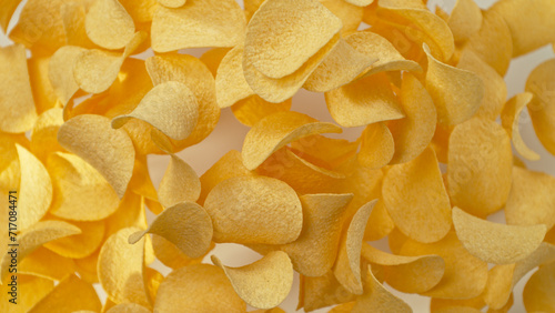 Freeze motion of flying fried potatoes chips on yellow background