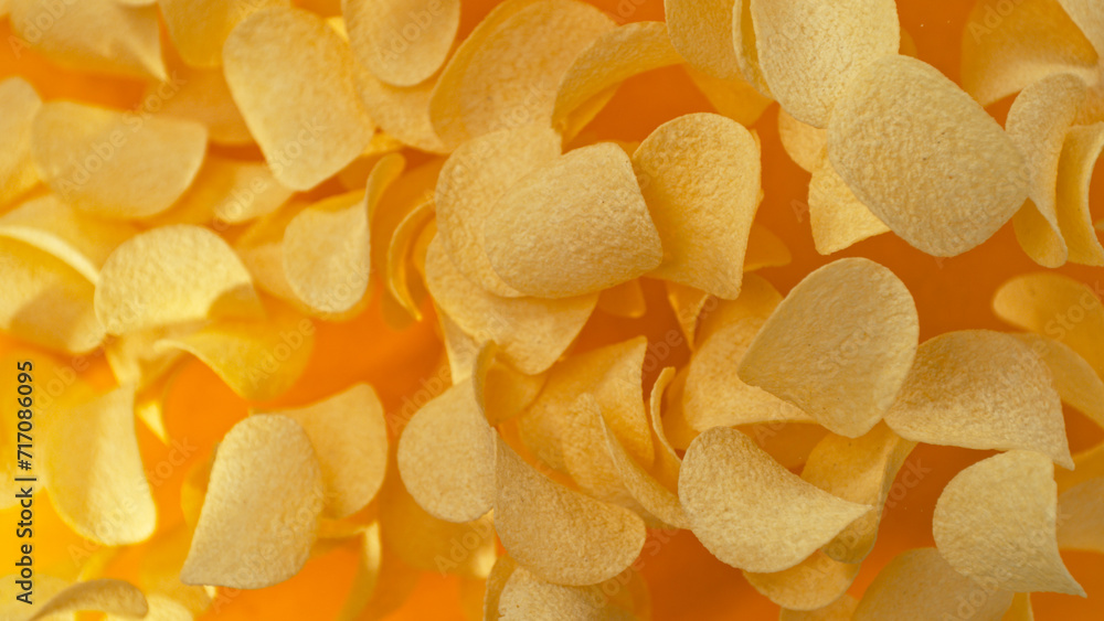 Freeze motion of flying fried potatoes chips on yellow background Freeze motion of flying fried potatoes chips on yellow background