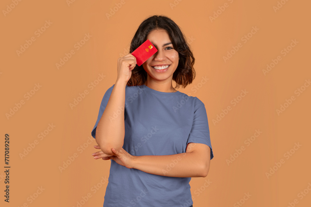 Cheerful middle eastern woman cover eye with credit card Cheerful middle eastern woman cover eye with credit card