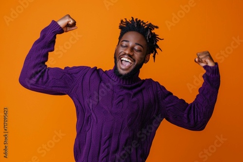 portrait of excited man in purple sweater dancing on orange background, delighted and fun person