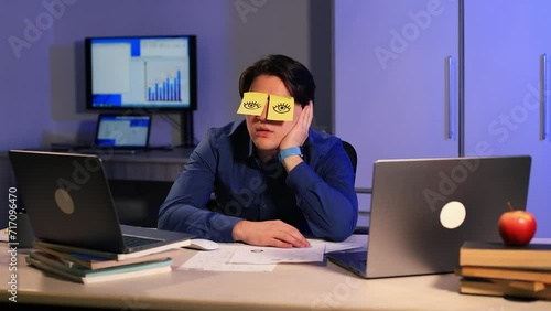 Lazy office worker napping at workplace covering eyes with sticky notes