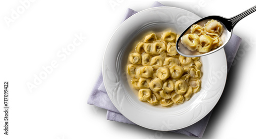 Soup plate and spoon with tortellini in broth with napkin