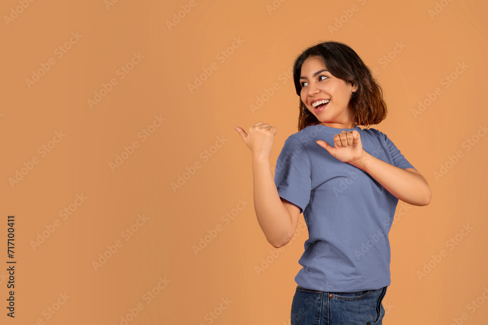 Cheerful young arab woman looking and pointing aside Cheerful young arab woman looking and pointing aside