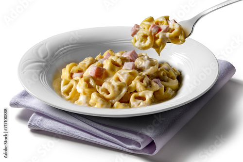 Tortellini soup plate and fork with cream and ham isolated on white background