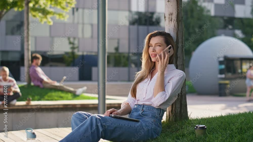 Attractive girl talking cell in urban park. Smiling woman student holding laptop Attractive girl talking cell in urban park. Smiling woman student holding laptop
