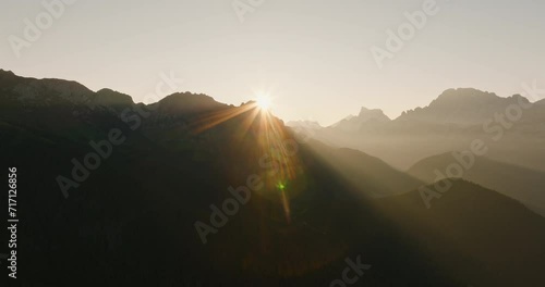 mountains dolomites italy alps bright sunrise at dawn from behind mountain peaks summer against blue sky aerial view lens flares. grandeur of mountain range. travel tourism concept