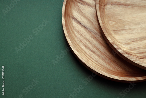 Wooden flat plates on a green background. The concept of ecological tableware. Products for modern kitchen. Zero emissions.