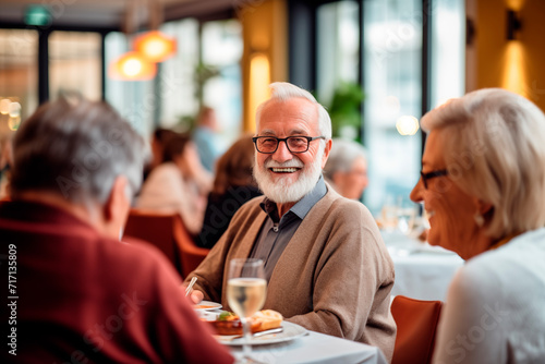 Elderly man smiling while enjoying an elegant dinner with friends at a restaurant.