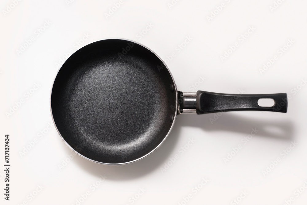 Cute new small pan on light background with shadow. A pan for frying one or two eggs Cute new small pan on light background with shadow. A pan for frying one or two eggs