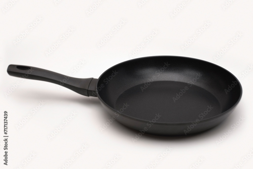 A large new pan on a light background with a dark shadow. A pan with high walls for frying or stewing food A large new pan on a light background with a dark shadow. A pan with high walls for frying or stewing food