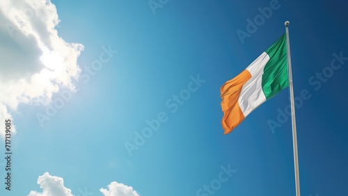 Irish flag waving against a blue sky with clouds photo
