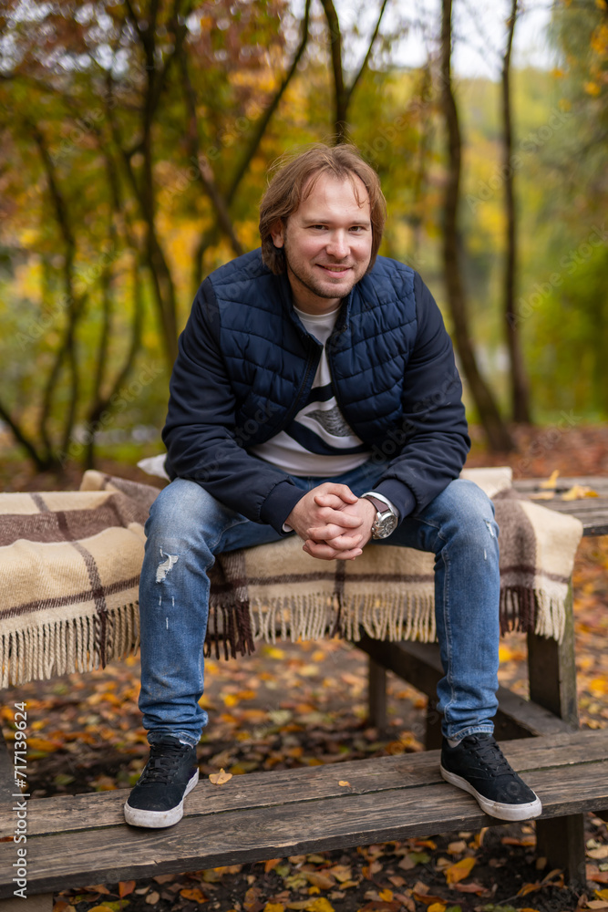 Man Sitting on Bench in Park, Enjoying Outdoor Environment. A man enjoys his time sitting on a bench in a serene park, surrounded by nature. Man Sitting on Bench in Park, Enjoying Outdoor Environment. A man enjoys his time sitting on a bench in a serene park, surrounded by nature.