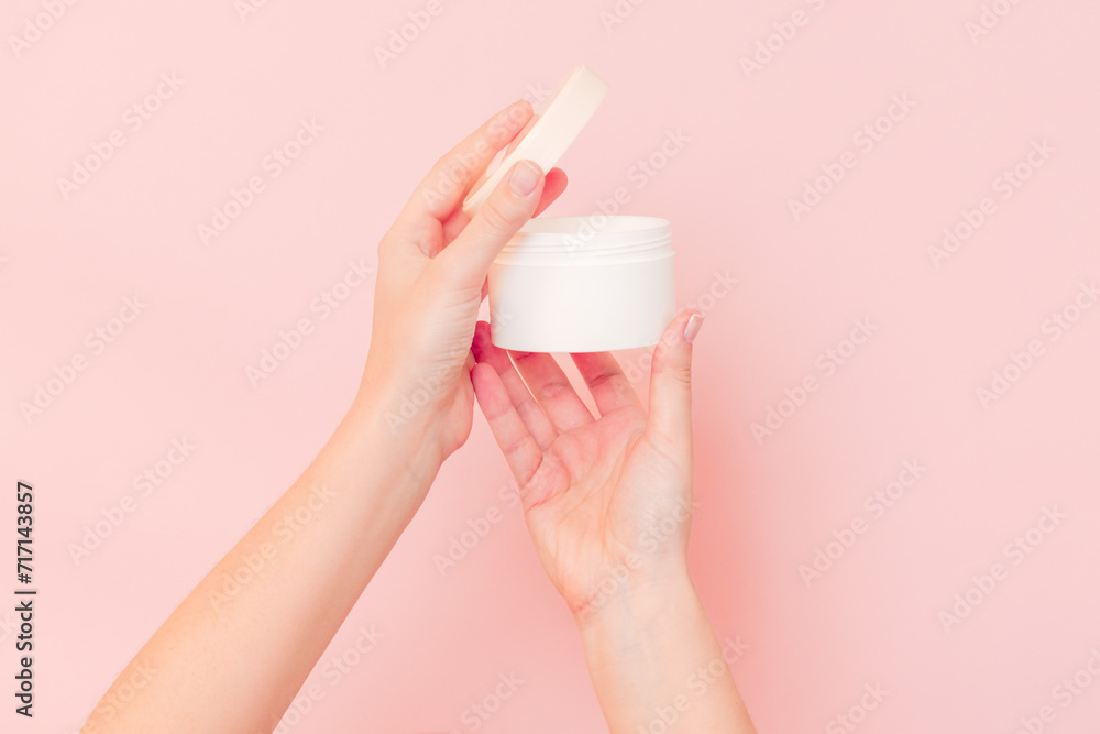 Round jar of cosmetic cream in hand on pink background. Cosmetics beauty mockup for product branding Round jar of cosmetic cream in hand on pink background. Cosmetics beauty mockup for product branding