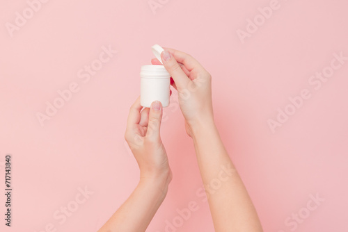 Hand holding plastic bottle on pink background. Cosmetics beauty mockup for product branding