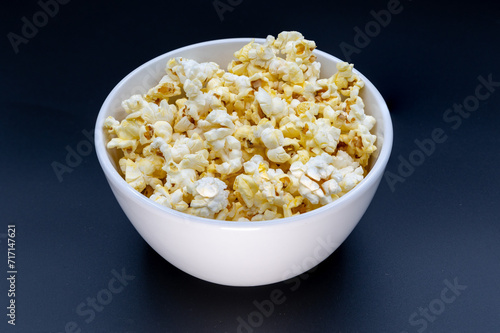 White bowl of microwave popcorn against a black background