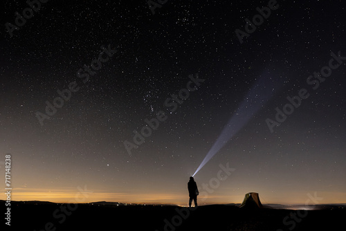 A wild camping man and his tent at night under a clear night sky in England