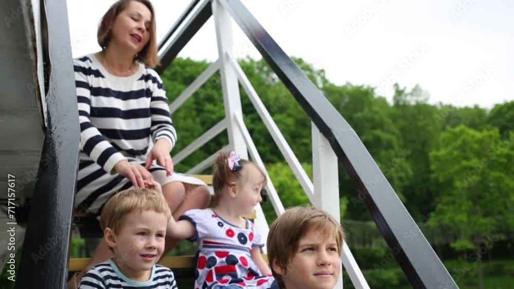 Mother and three children sit on the stairs of the pleasure boat