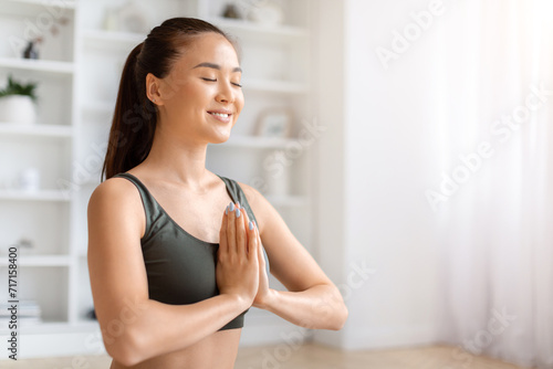 Beautiful asian woman practicing yoga with eyes closed and making namaste gesture Free Download Beautiful asian woman practicing yoga with eyes closed and making namaste gesture - GFXLoad