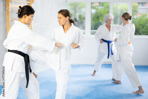 Karate lessons in the gym - women in pairs train punches and kicks