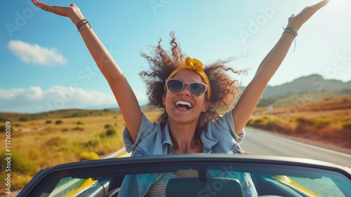 Joyful woman with arms raised in a convertible car, sunny day photo
