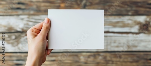 Close-up of a female hand holding a blank white paper for text and design.