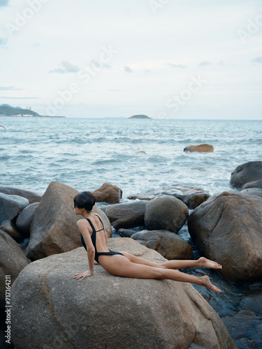 Exquisite Summer: A Sensual Swimwear Model Posing on a Rock, Surrounded by Sand and Crystal-clear Ocean Waters