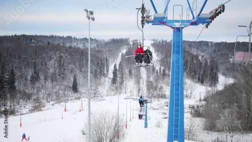 Woman and boy rise on ropeway at winter day in ski resort photo