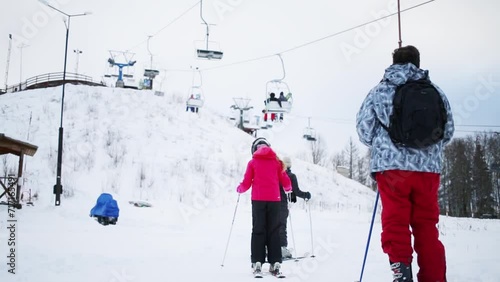 Man with two children skiers go to ropeway at winter day photo