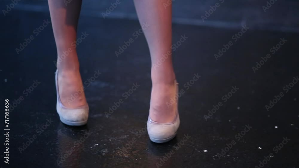 A woman in high heels walking from side to side on the black floor A woman in high heels walking from side to side on the black floor