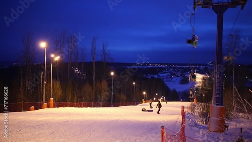 Snowboarders and funicular at night in skiing sports complex photo
